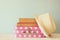 Photo of pink suitcase with polka dots, fedora hat and stack of books over wooden table, retro style image