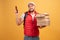Photo of pizza man receives orders from customers via smart phone, holds many carton boxes with fast food, has unpleasant look to