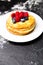 Photo of plate with pancakes, blueberries, raspberries dusted with icing sugar