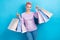 Photo of pleasant lovely person with short haircut wear stylish sweatshirt holding shopping bags isolated on blue color