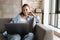 Photo of pleased nice girl using laptop while sitting on couch