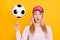 Photo portrait amazed woman in cap keeping soccer ball on finger stare isolated bright yellow color background
