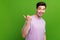 Photo portrait of attractive young guy point cheerful empty space dressed stylish purple clothes isolated on green color