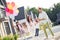 Photo portrait of big family wearing birthday cones while father lifts up boy outdoors in summer on street