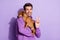 Photo portrait cheerful man smiling keeping little brown puppy showing v-sign  pastel purple color background
