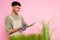 Photo portrait of curly gardener cut green grass with scissors working with plants isolated on pastel pink color