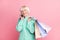 Photo portrait of cute granny talking on cellphone keeping black friday packages after sale isolated on pastel pink