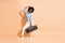 Photo portrait of energetic black skinned woman holding boom box in one hand dancing isolated on pastel beige colored