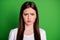 Photo portrait of frowning upset woman isolated on vivid green colored background