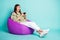 Photo portrait full body view of excited gamer girl holding joystick with two hands sitting on purple bean bag chair