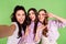 Photo portrait of girls smiling overjoyed taking selfie showing v-sign gestures smiling isolated on bright green color