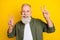 Photo portrait of grandfather smiling showing v-sign gesture isolated vivid yellow color background