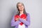 Photo portrait of granny hugging big red paper heart card wearing violet shirt isolated on grey colored background