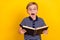 Photo portrait little boy wearing t-shirt glasses amazed reading book isolated vibrant yellow color background