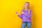 Photo portrait of lovely young lady look fingers point empty space dressed stylish violet clothes isolated on yellow