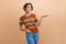 Photo portrait of lovely young lady palm hold look empty space wear trendy orange print garment isolated on beige color