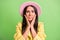 Photo portrait of nervous stressed woman touching cheekbones hands staring in pink hat isolated on vibrant green color