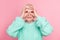 Photo portrait of playful senior lady blonde hair pretending wearing eyeglasses careless funny isolated on pastel pink