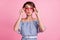 Photo portrait of pouting girl touching rose-tinted heart-shaped glasses  on pastel pink colored background