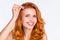 Photo portrait of pretty girl with wavy ginger hair smiling applying liquid essence with pipette on skin isolated on