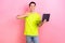Photo portrait of pretty teenager guy thumb up hold netbook do homework dressed stylish yellow outfit isolated on pink