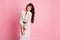 Photo portrait of pretty woman with long wavy hair wearing dotted white dress smiling  pastel pink color