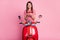 Photo portrait of pretty woman sitting on red moped keeping mobile phone smiling isolated on pastel pink color