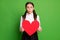 Photo portrait of schoolgirl holding big red cutout heart pouting isolated on vivid green colored background