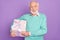 Photo portrait of senior man keeping wrapped box with present smiling isolated on pastel violet color background