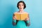 Photo portrait of shocked impressed female student holding yellow book  on vivid blue color background