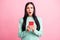 Photo portrait of shocked upset girl holding phone with two hands  on pastel pink colored background