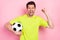 Photo portrait shouting man wearing bright t-shirt keeping soccer ball gesturing like winner isolated pastel pink color