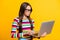 Photo portrait of smart schoolgirl wearing spectacles working with laptop reading concentrated isolated on bright yellow