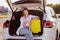 Photo portrait smiling girl put baggage in the car going to airport using smartphone