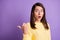 Photo portrait of stunned brunette girl pointing thumb at black space behind back isolated on vivid violet colored