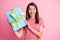 Photo portrait of surprised happy birhtday girl holding wrapped gift wearing t-shirt smiling isolated on pastel pink