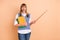 Photo portrait of teacher keeping pile books showing pointer amazed opened mouth isolated on pastel beige color