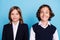 Photo portrait two school mates smiling in uniform sitting on lesson isolated pastel blue color background