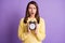 Photo portrait of upset anxious woman holding black clock in two hands with open mouth isolated on vivid violet colored