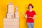 Photo portrait of woman demonstrating stack carton of boxes shipment service isolated vibrant yellow color background