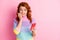 Photo portrait of woman in panic biting nails holding phone in one hand isolated on pastel pink colored background