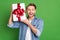 Photo portrait of young guy smiling in casual outfit trying to guess what in gift box isolated on vivid green color
