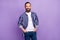 Photo of positive cool bearded guy hands pockets look camera wear striped shirt isolated violet color background
