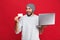 Photo of positive guy holding credit card and silver laptop isolated over red background