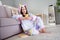 Photo of positive influencer lady sit floor hold telephone read post comment feedback wear cozy unicorn kigurumi indoors