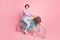 Photo of positive lady drive bike deliver flowers wear violet blouse pants shoes isolated pink color background
