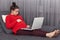 Photo of pregnant woman feels lazy, looks attentively at laptop computer, poses at sofa, watches film online, enjoys free internet