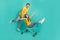 Photo of pretty carefree married couple wear yellow t-shirts riding shopping tray having fun isolated teal color