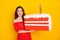 Photo of pretty positive girl lick lips look interested large cake isolated on yellow color background