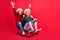Photo of pretty positive schoolchildren wear knitted pullovers rising hands arms sledding smiling isolated red color